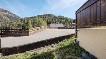 A stable with a wooden fence, a gravel path, and a mountain backdrop.