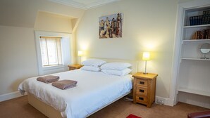 Ein Schlafzimmer mit einem Bett, zwei Nachttischen, einem roten Teppich, einem Fenster mit Jalousien, einem Bild an der Wand und einem Bücherregal.