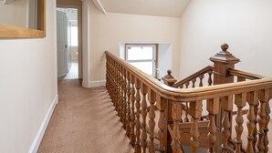 Eine Teppichstufenreife Treppe mit hölzernem Geländer und Spindeln, die zu einer Tür mit Fenster führt.