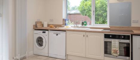 A compact kitchen with a washing machine, a dishwasher, and a stove.