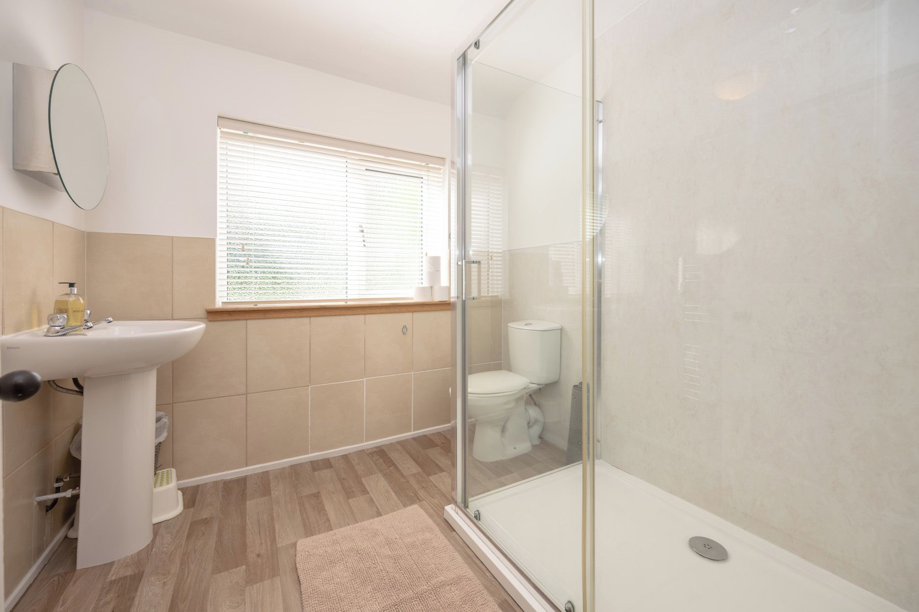 Baño con cabina de ducha de vidrio, lavamanos e inodoro.