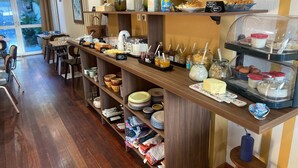 Un bufé de desayuno con diversos alimentos, una máquina de café y vistas al exterior.