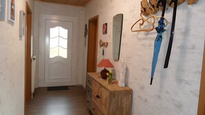 Ein Flur mit einem Holzkapfen, einem Spiegel, einer Lampe und einer Tür mit Fenster.