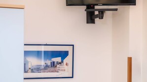 Une pièce avec un téléviseur fixé au mur, un tableau encadré et une table sur laquelle se trouve un panier de citrons.