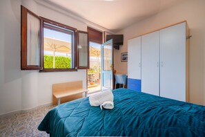 Un dormitorio con cama, un banco, un armario y una ventana con vistas a zonas verdes.