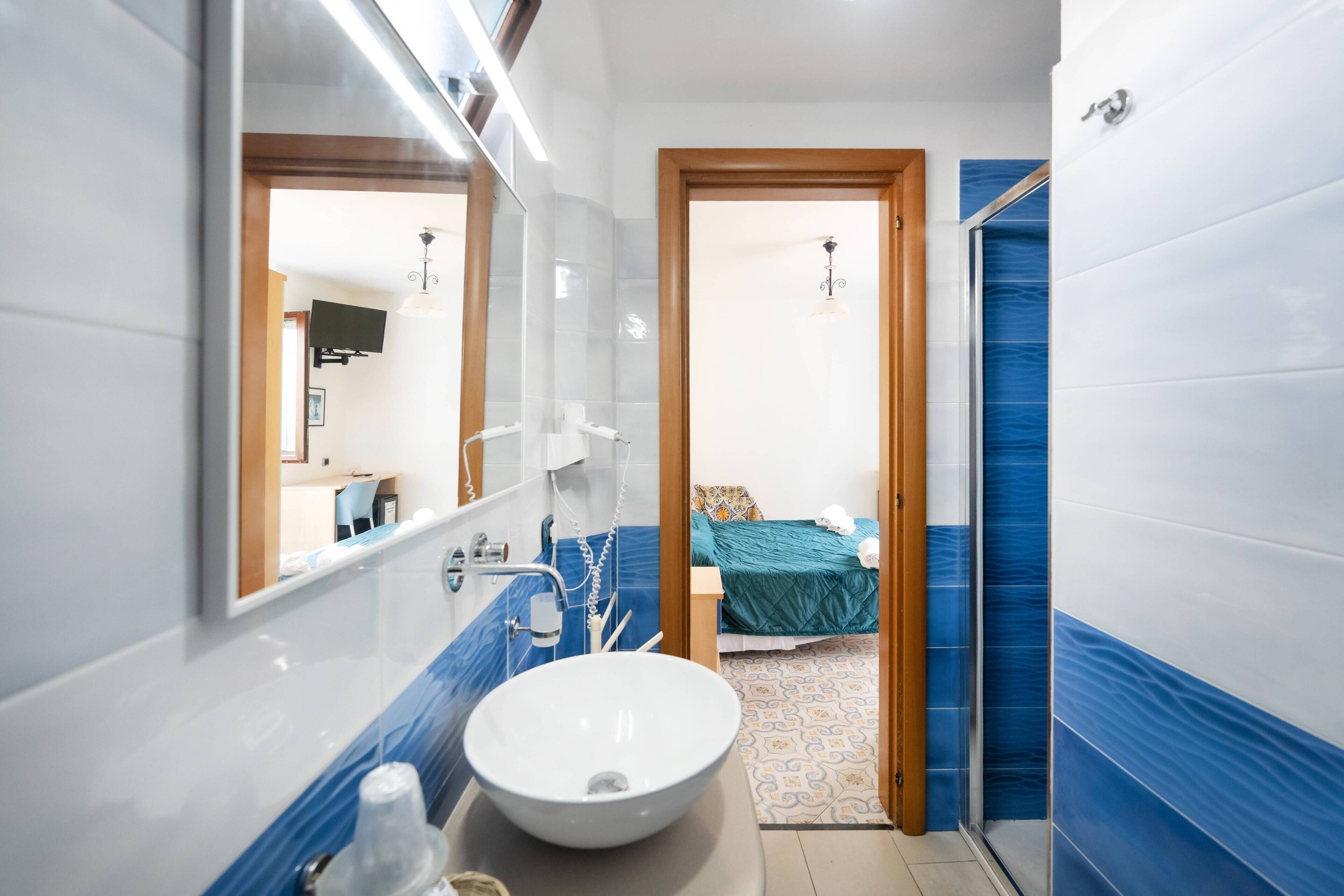 Un bagno con un lavandino bianco, uno specchio e una doccia.