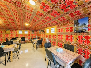 A restaurant with patterned walls and ceiling, multiple tables, and chairs. - Nigmt Siwa Hotel (Siwa)