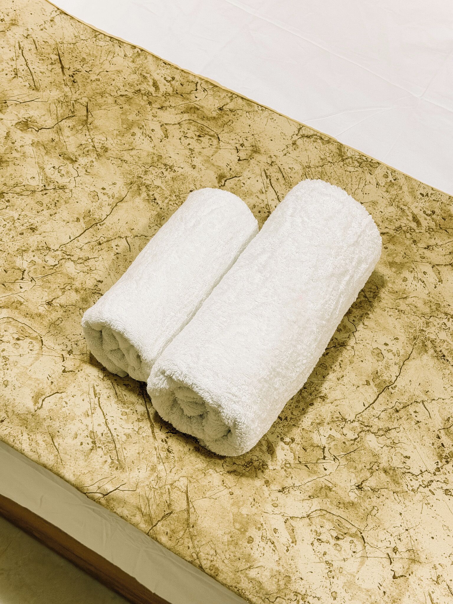 A bathroom with a marble countertop and two rolled towels.