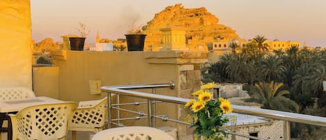 A terrace with outdoor seating, a vase with sunflowers, and a view of a historic building.