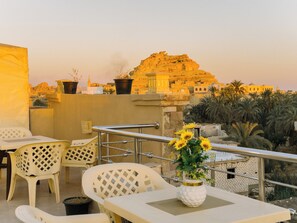 Una terraza con mesas al aire libre, un jarrón con girasoles y vistas a un edificio histórico.