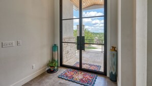 Ein Zimmer mit einer Schiebetür zum Balkon, einem Blumentopf, einem Teppich und einer hohen Vase.