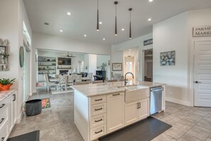 A modern kitchen with a central island, white cabinetry, and pendant lighting. - Amazing 4-bedroom House with Pool, Golf Simulator, and Batting Cage. (Lago Vista)