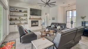 Ein modernes Wohnzimmer mit Kamin, Ledersofas, einem Couchtisch und einer Wand mit Steinverkleidung.