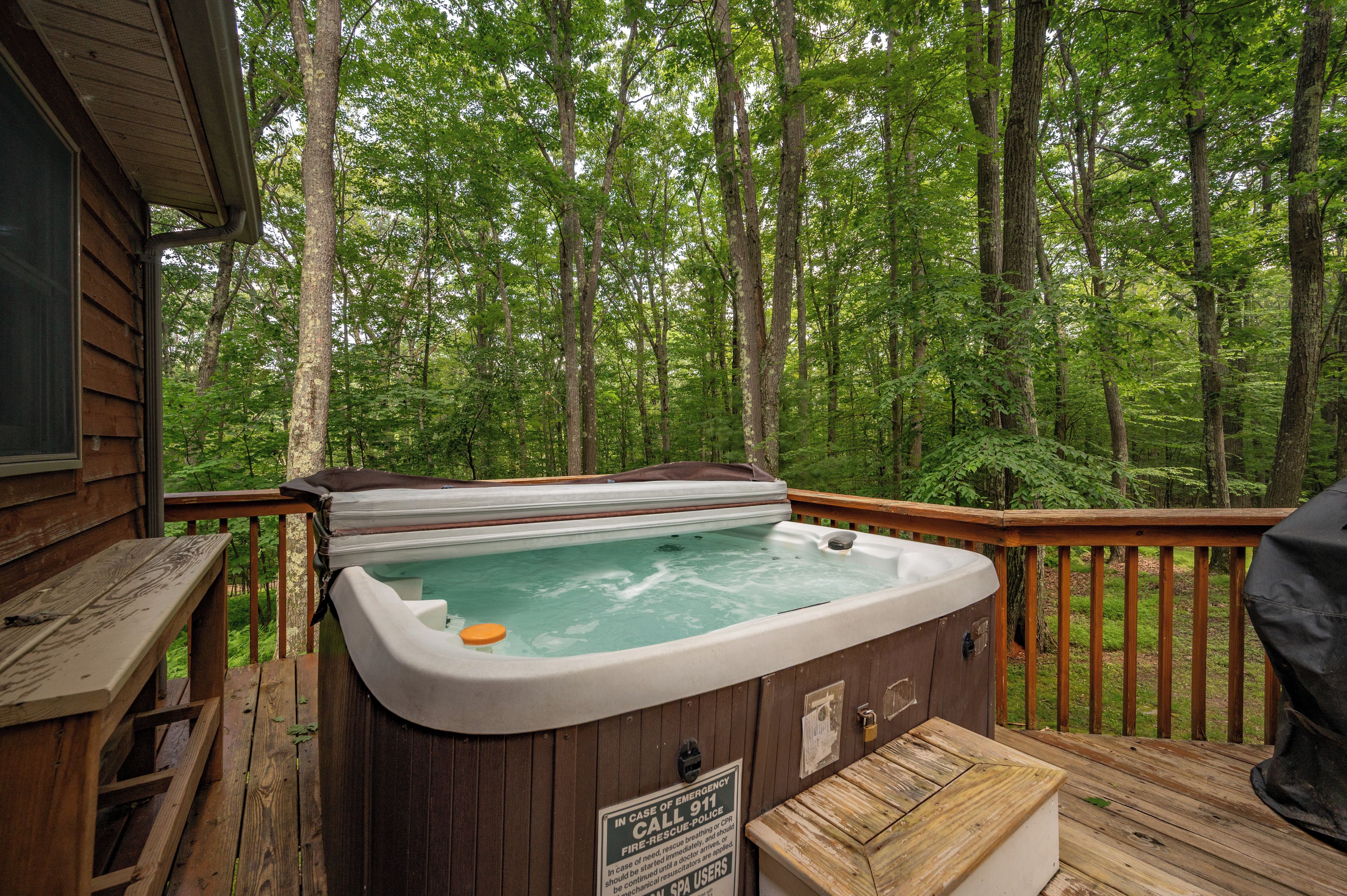 A hot tub on a wooden deck surrounded by a forest.