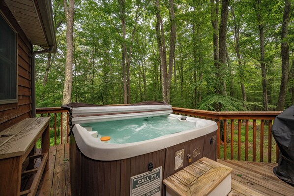 A hot tub on a wooden deck surrounded by a forest. - New! Lake Area Chalet w/ Hot Tub (Swanton)