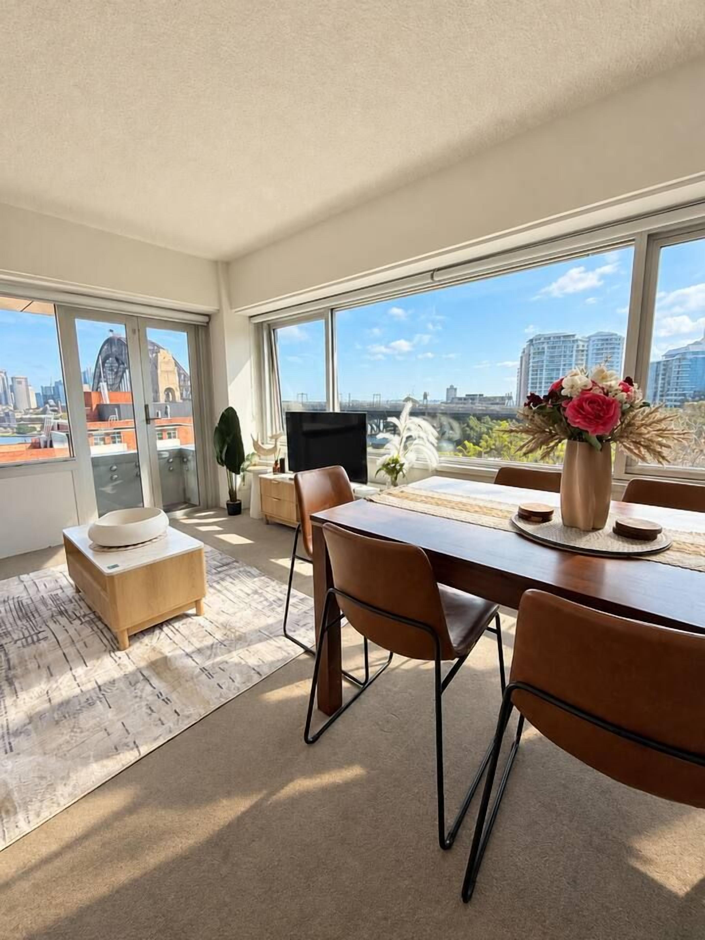 A modern living room with a dining area, large windows, and a view of the cityscape.