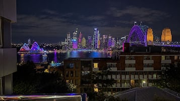 A nighttime cityscape with illuminated buildings and a bridge.