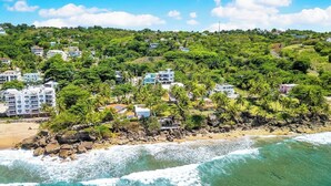 Uma área residencial costeira com casas rodeadas por vegetação exuberante e uma praia.