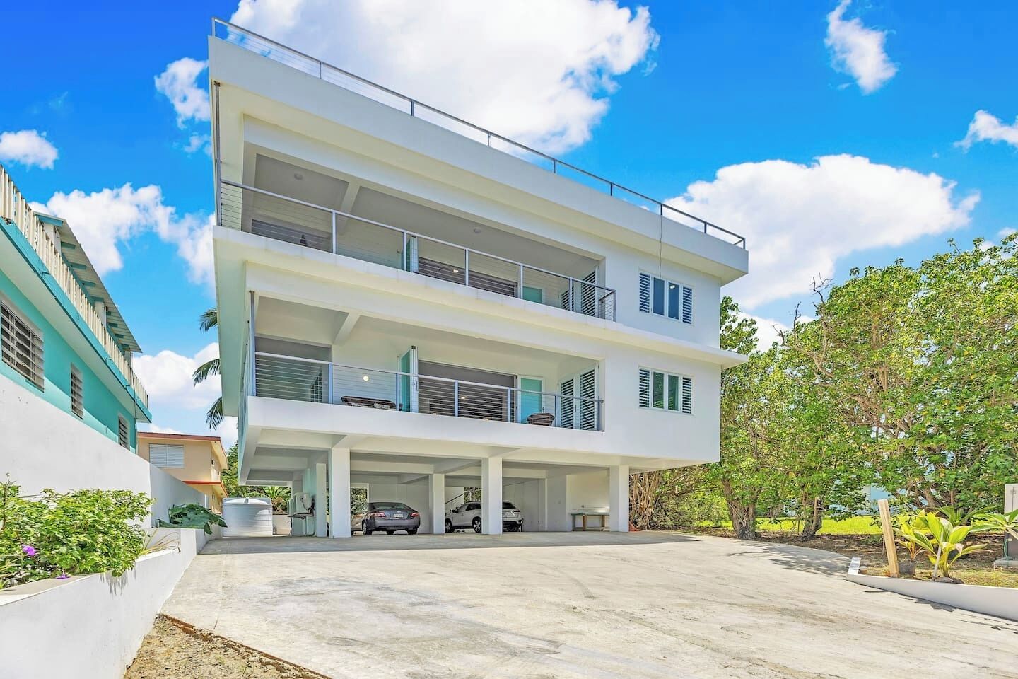 Un edificio moderno a più piani con tetto piatto, balconi e un’area di parcheggio.