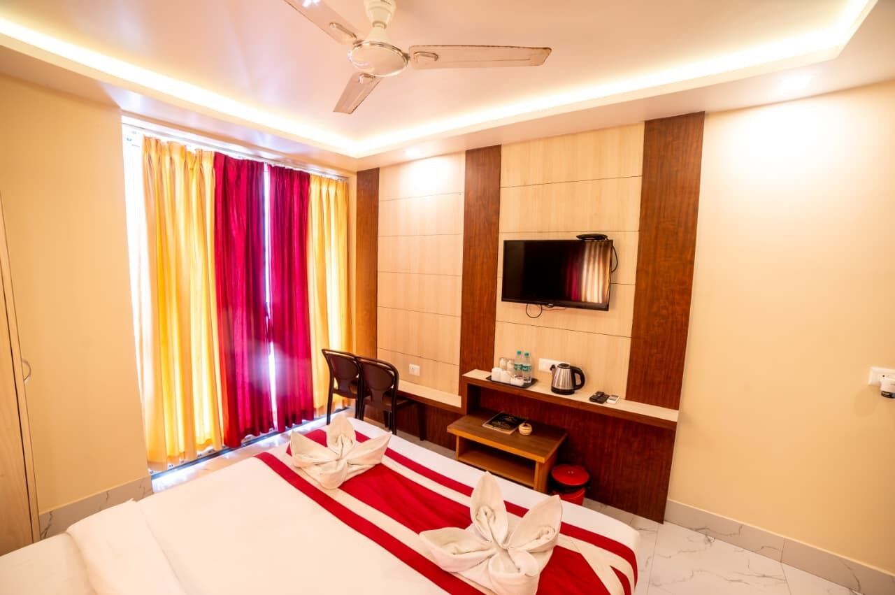 A hotel room with a bed, a desk, a television, and a window with curtains.