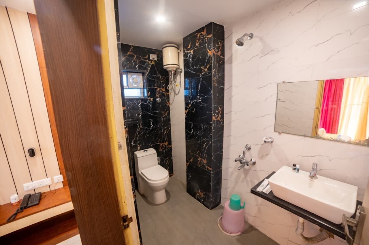 A bathroom with a toilet, sink, mirror, and marble walls.