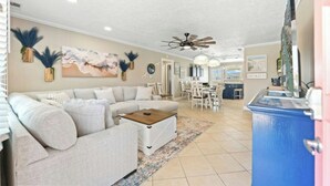 A living room with a sofa, coffee table, and a dining area with chairs and a table. - Silver Sand Dollar - Channel House - Firepit (North Myrtle Beach)