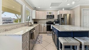 A modern kitchen with granite countertops, stainless steel appliances, and a large island with bar stools. - Silver Sand Dollar - Channel House - Firepit (North Myrtle Beach)