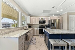 Eine moderne Küche mit Granit Arbeitsplatten, Edelstahlgeräten und einer großen Kochinsel mit Barhocker.