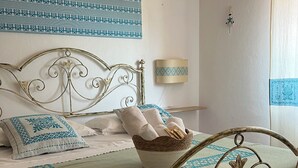 Ein Bett mit Metallgestell, ein gewebter Korb darauf und eine Wandlampe.