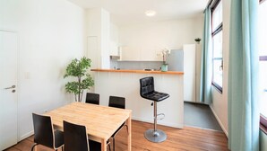 Una cocina moderna con una mesa de madera y sillas negras, un taburete de bar y una planta en maceta.