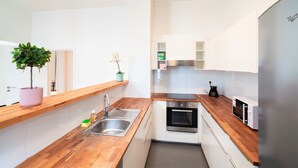 Una cocina moderna con mostradores de madera, un lavamanos de acero inoxidable, un horno empotrado y un refrigerador.