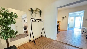 Ein Zimmer mit Holzboden, einem schwarzen Metallgestell, einer Topfpflanze und einem Spiegel an der Wand.