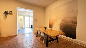 Ein Essbereich mit Holztisch und -stühlen, einer großen Wandmalerei und einem Flur zu einem weiteren Zimmer.
