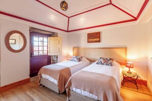 Ein Hotelzimmer mit zwei Betten, einer Holztür, einem Spiegel und einem Bild an der Wand.