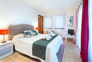 Ein Hotelzimmer mit Bett, Nachttischen, einem Fernseher und einem Fenster.