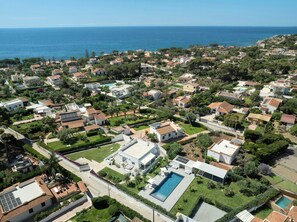 An aerial view of a residential area with houses, a swimming pool, and a clear view of the sea. - Modern villa with pool in Fontane Bianche (Siracusa)