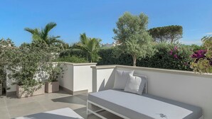 A rooftop terrace with a white bed, potted plants, and a clear blue sky. - Modern villa with pool in Fontane Bianche (Siracusa)