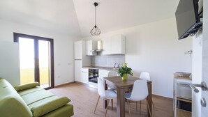 Una cocina moderna con armarios blancos, una mesa de comedor con sillas y un sofá verde.