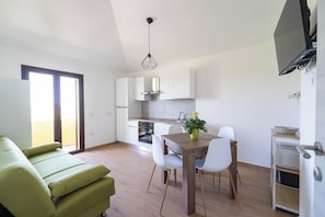 Eine moderne Küche mit weißen Schränken, einem Esstisch mit Stühlen und einem grünen Sofa.