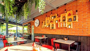 A restaurant with brick walls, wooden tables, and red chairs.
