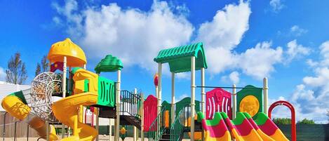 A playground with various play structures including slides and climbing areas.
