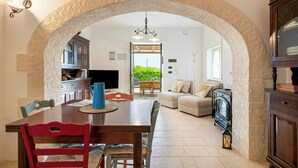 A dining area with a stone archway, a wooden table, and chairs. - Apulian trullo with pool among vineyards (Martina Franca)