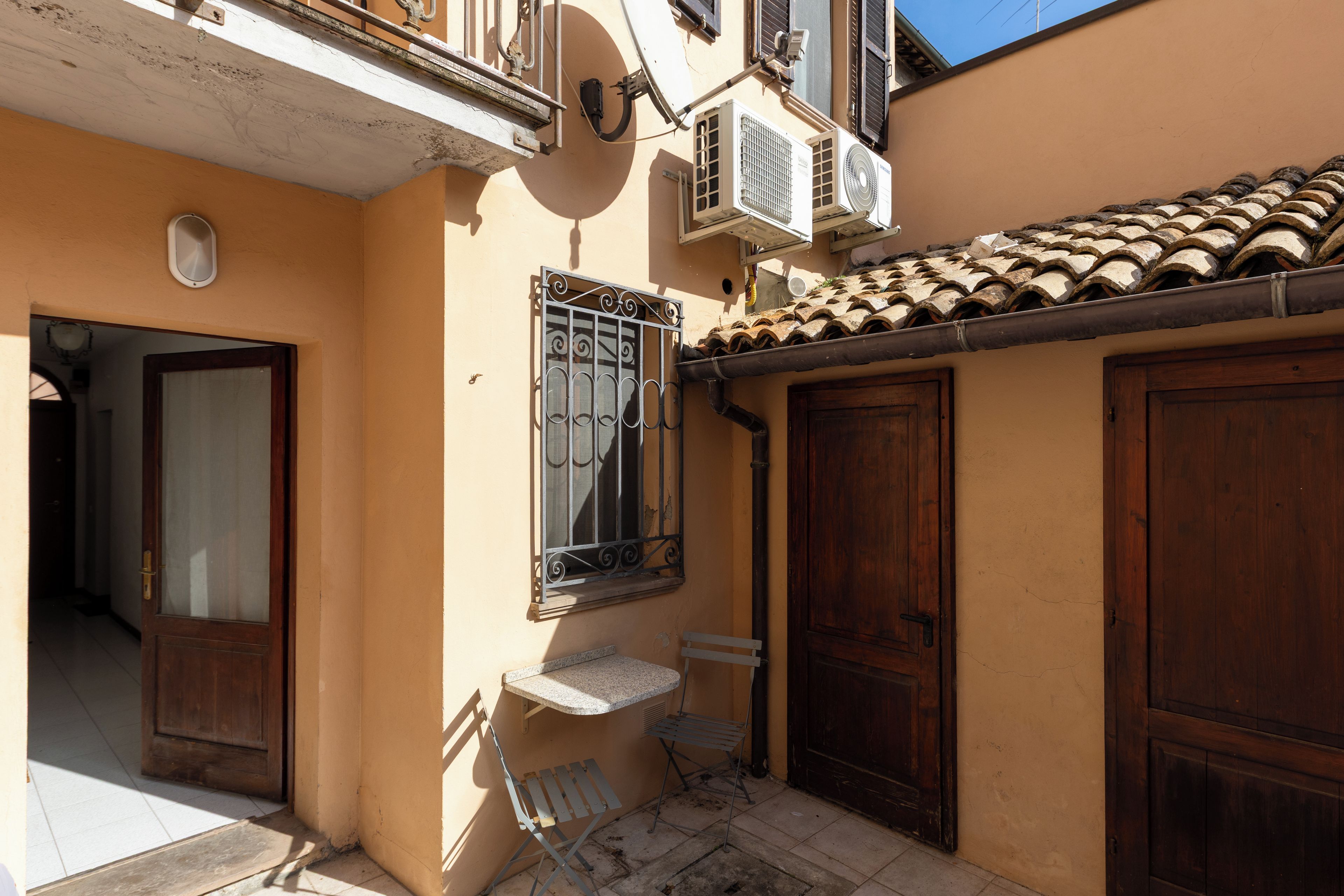Un edificio con tetto in tegole, una finestra con inferriate e una porta.