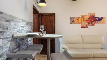 Una zona pranzo con tavolo apparecchiato per due, una divano e arte astratta appesa al muro.