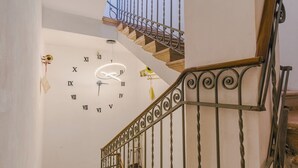 Een trap met een klok aan de muur, een metalen leuning en een decoratieve lamp.