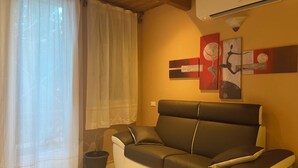 Een woonkamer met een bank, een potplant en abstracte kunst aan de muur.