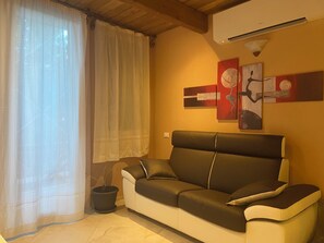 Ein Wohnzimmer mit einer Couch, einem Blumentopf und abstrakter Wandkunst.
