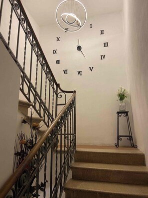 Un escalier orné de rampes en métal ouvragé et une horloge murale.