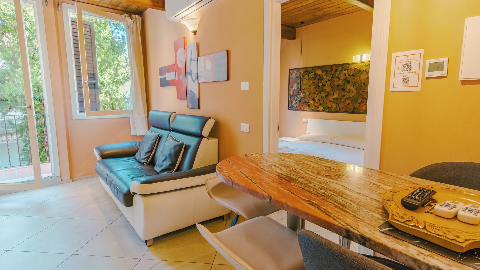 Een moderne woonkamer met een bank, een eettafel met een afstandsbediening, en kunst aan de muren.