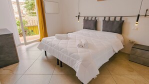 Een hotelkamer met een bed, een klein tafeltje, een stoel, een raam met gordijnen en uitzicht op de omgeving.